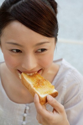 View of a young woman eating bread --- Image by © Image Werks/Corbis