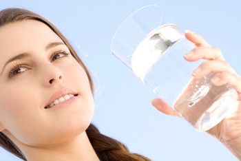 Portrait of a young woman holding a water glass, outdoors --- Image by © Elie Bernager/Onoky/Corbis