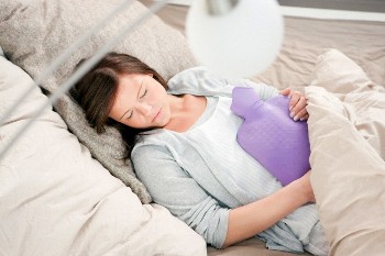 Woman sleeping with hot water bottle --- Image by © Nils Hendrik Mueller/cultura/Corbis