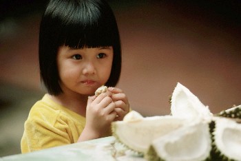 ca. 1989, Singapore --- Little Girl Eating Durians --- Image by © Michael S. Yamashita/Corbis