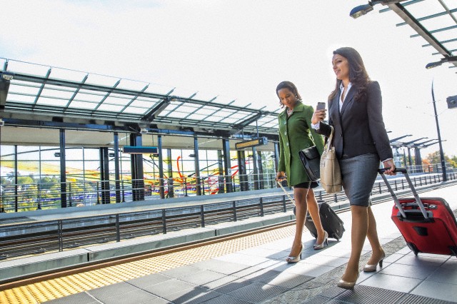 Businesswomen rolling luggage on train platform