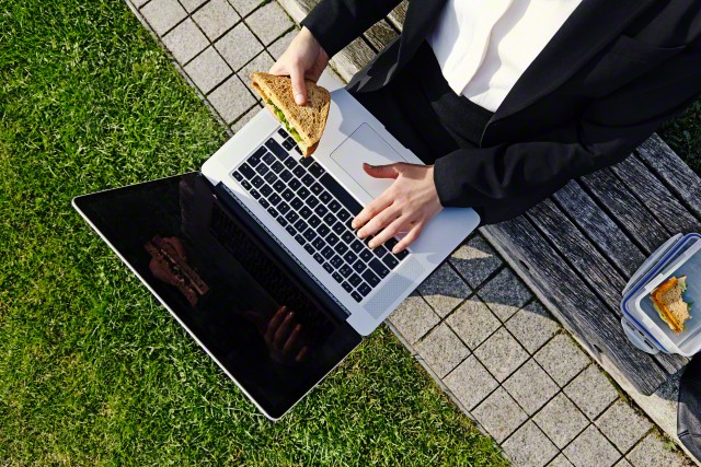 woman eating lunch and working in park.